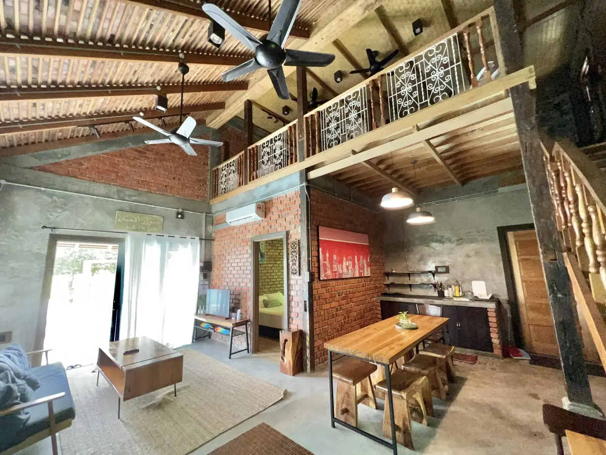 Double-height living hall of Rumah Wan with loft railing, ceiling fans and singgora roof